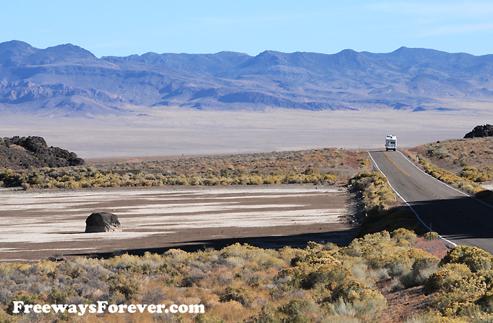 Solitary rock boulder on sand next to highway in northern Nevada