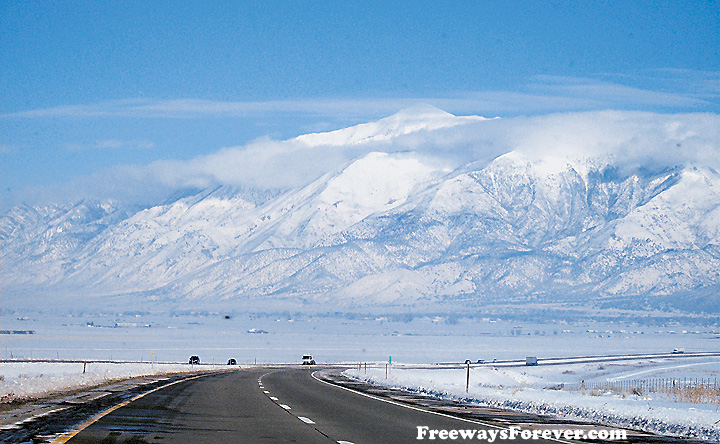 Interstate 15 highway in Utah with snow-covered Wasatch Mountain Range in distance near Nephi