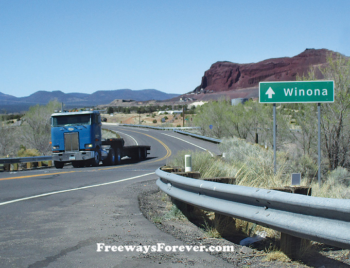 Peterbilt COE cabover truck rolls along old Route 66 in Arizona past a sign for Winona